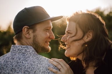 Verliebtes Paar im Sonnenuntergang: Intimer Blick, fliegende Haare, eingefangen von Kathy Audrey Photography.