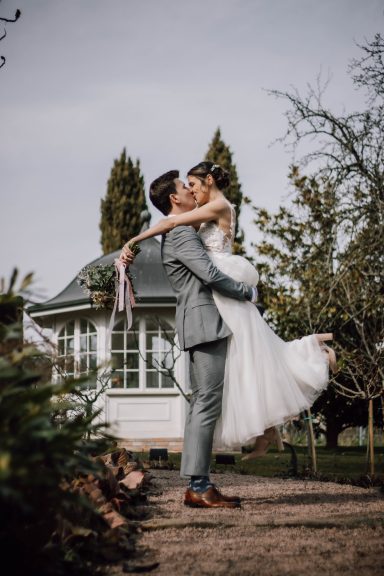 Bräutigam hebt Braut vor Pavillon in Bad Dürkheim und sie küssen sich, festgehalten von Kathy Audrey Photography.