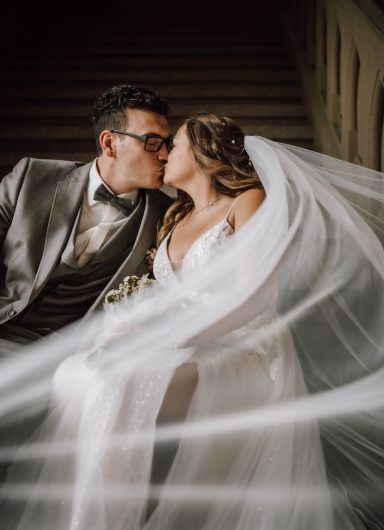 Wedding Shooting im Kloster Maulbronn, Hochzeitspaar küsst sich auf der Treppe und der Schleier der Braut weht im Wind im Kloster Maulbronn