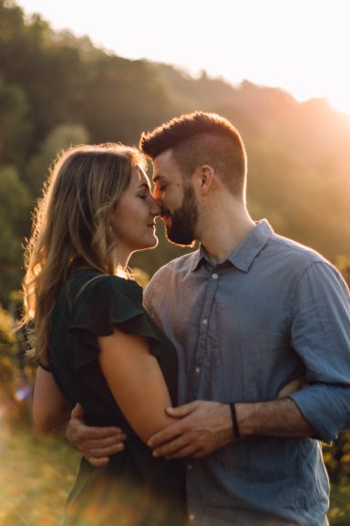 Liebespaar im Sonnenuntergang: Beide Gesichter sind ganz nah beieinander, sie wirken, als würden sie sich gleich küssen.